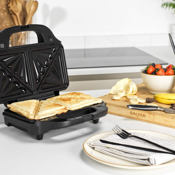 Black sandwich maker with two toasted sandwiches on kitchen counter