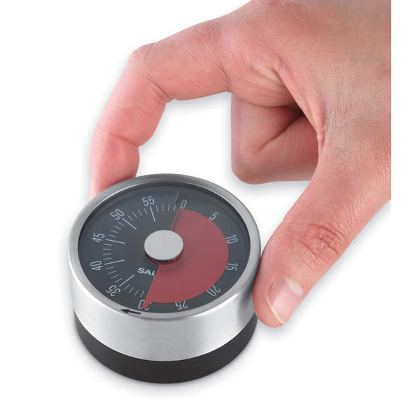 Silver mechanical kitchen timer with black base, being set by hand