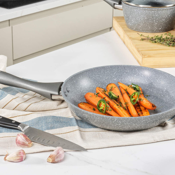 Grey non-stick cookware set displayed with food, including frying pans and saucepans