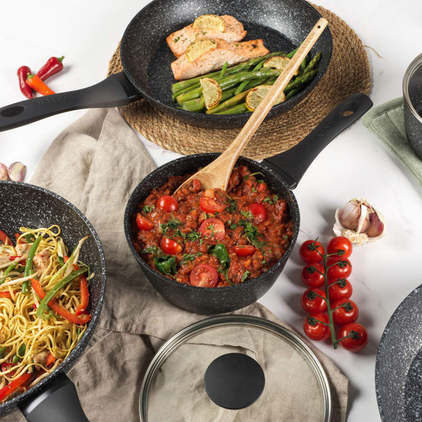 Set of non-stick black pans with cooked dishes, shown from above for product display