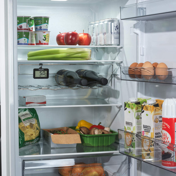 Interior view of fridge stocked with drinks, fruit, eggs, vegetables and cartons