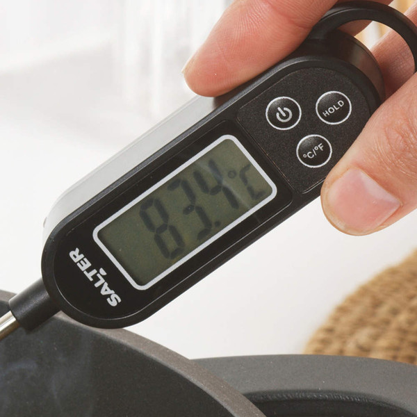 Digital cooking thermometer with black display next to wooden utensils in kitchen drawer