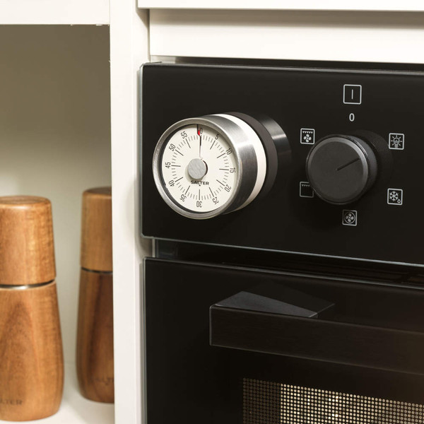 Stainless steel mechanical kitchen timer attached to oven, side view
