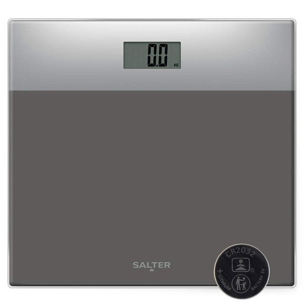 Grey glass digital bathroom scale with LCD display, shown with included CR2032 battery.