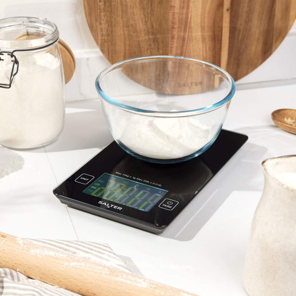 Digital kitchen scale with glass bowl of flour in a baking setting