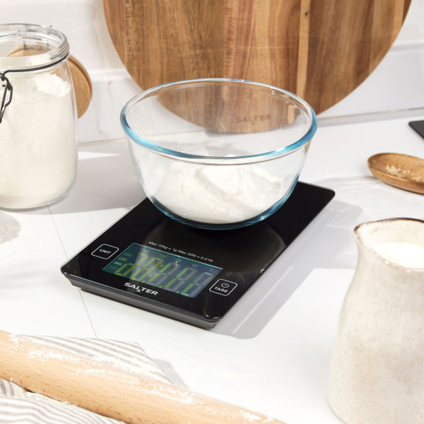 Black digital kitchen scale with large display, shown on worktop in a baking setting