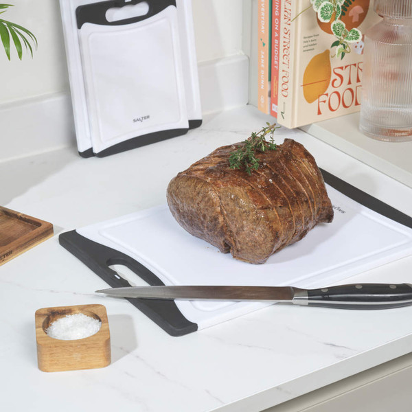 Set of three white and black plastic chopping boards with handles, shown stacked.