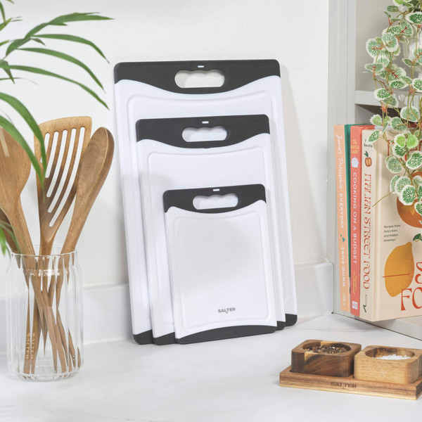 Set of three white chopping boards with black handles, shown side by side.