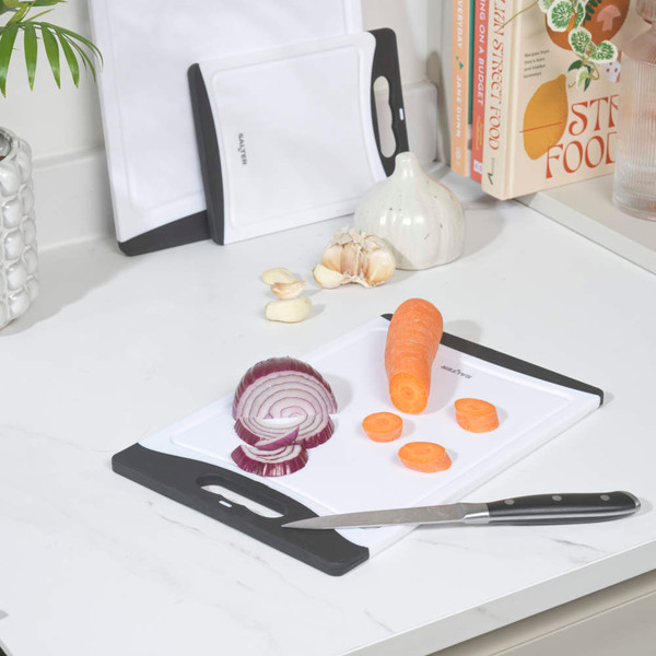 White plastic chopping board with black edge, lime cut in pieces and knife on kitchen counter