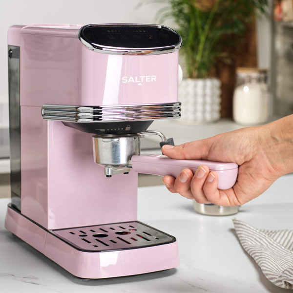 Pink Salter espresso coffee machine on kitchen counter with hand holding portafilter