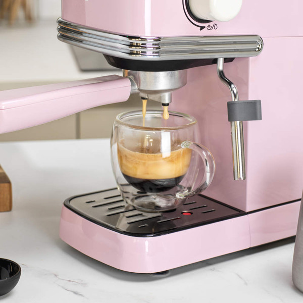 Pink espresso machine in kitchen, hand removing water tank for refilling or cleaning