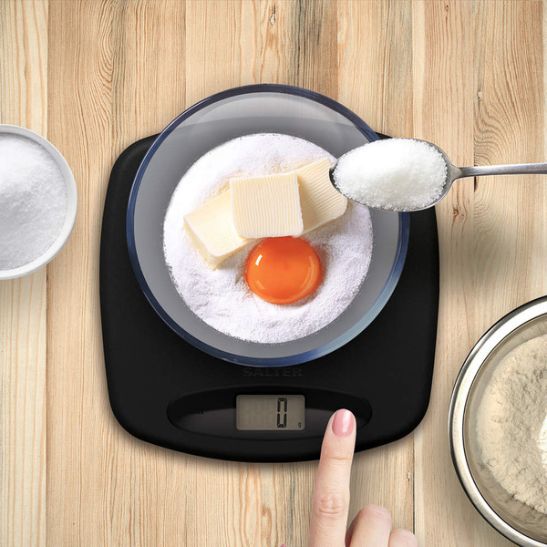 Digital kitchen scale with bowl, showing flour, butter and an egg being weighed