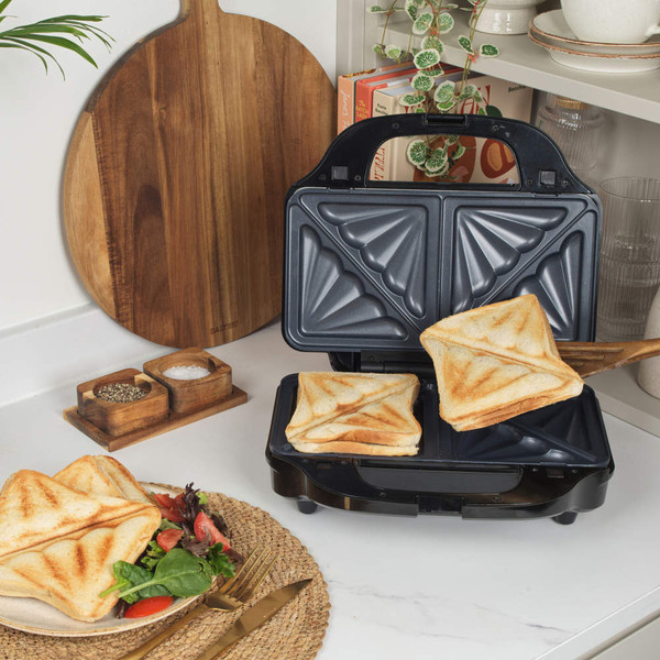 Black sandwich toaster with two toasted sandwiches on kitchen counter