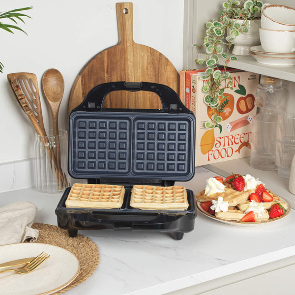 Square waffle maker in black on kitchen worktop, with cooked waffles served