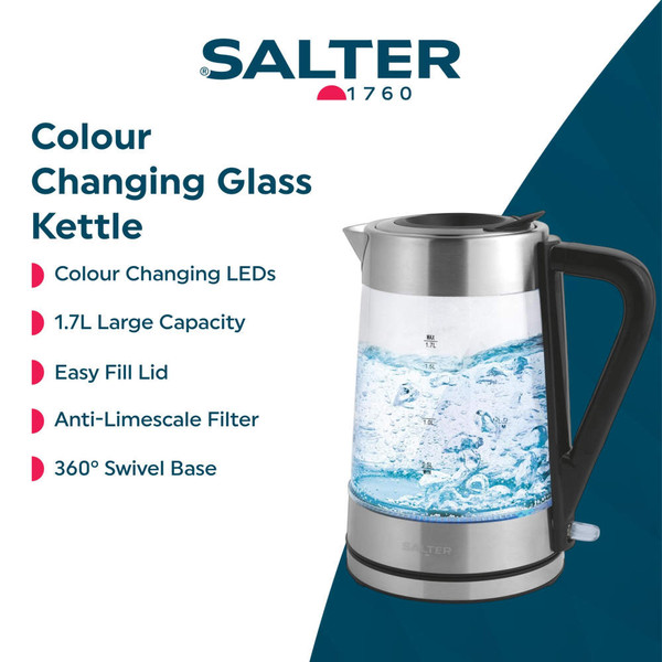 Glass electric kettle with silver accents being filled with water at a kitchen sink