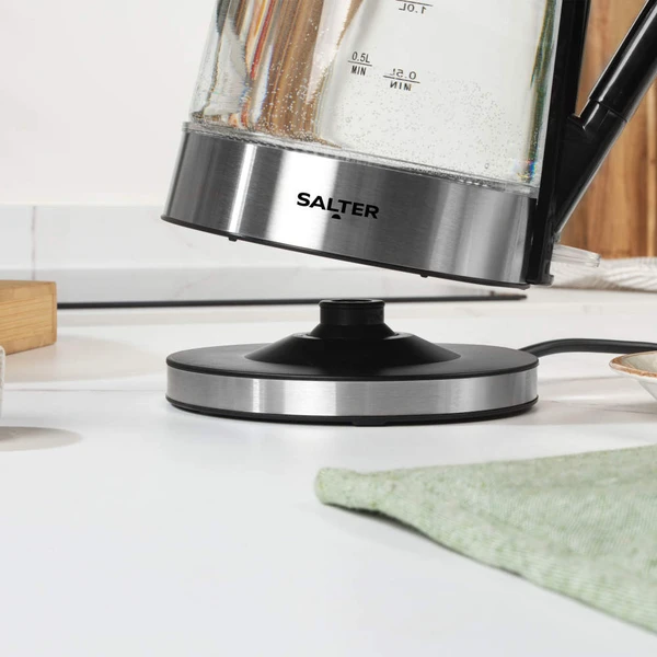 Glass electric kettle pouring water, stainless steel base, Salter brand visible