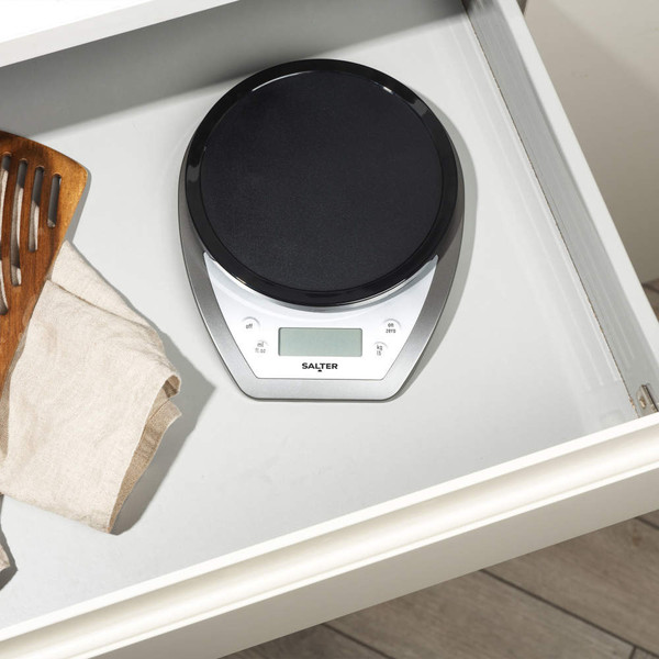 Digital kitchen scale with black platform on worktop, Salter brand visible above display
