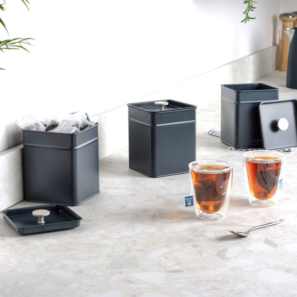 Set of three dark grey metal tea, coffee and sugar canisters on kitchen counter