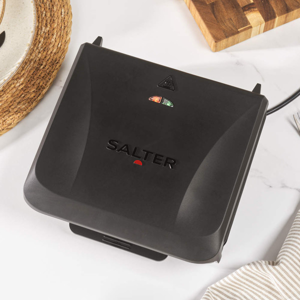 Salter black sandwich toaster closed on kitchen counter, shown from above.