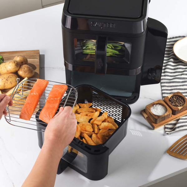 Black double drawer air fryer on kitchen counter with control panel, food served beside.