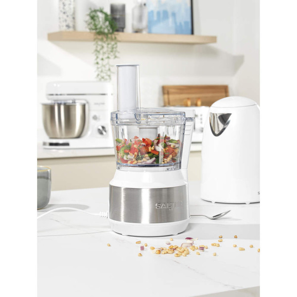White and silver food processor with chopped vegetables inside, shown on a kitchen counter