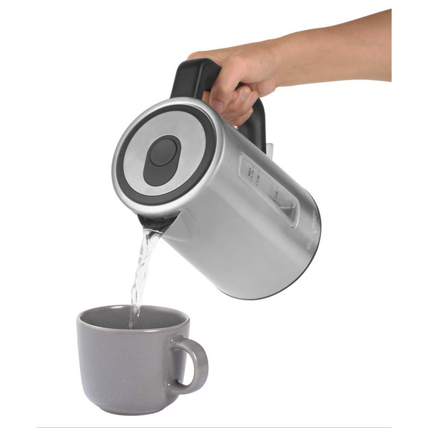 Silver electric kettle pouring hot water into grey mug, hand holding handle