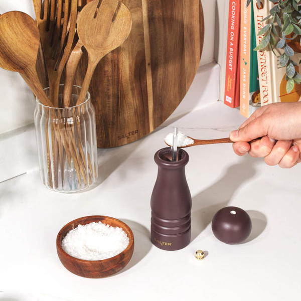Burgundy wooden pepper mill with gold top, shown upright on white background