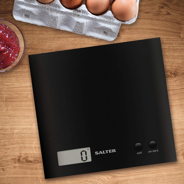 Black digital kitchen scale with touch buttons and display, shown on wooden worktop