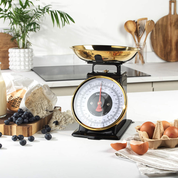 Gold colour mechanical kitchen scale with bowl, shown weighing fresh cherries