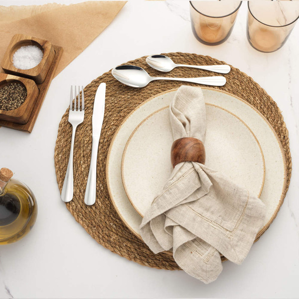 Table setting with cream stoneware plate, woven placemat, linen napkin and silver cutlery