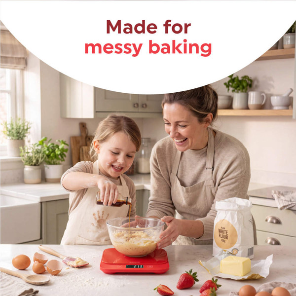 Red digital kitchen scale on counter with eggs, strawberries, and cake in background