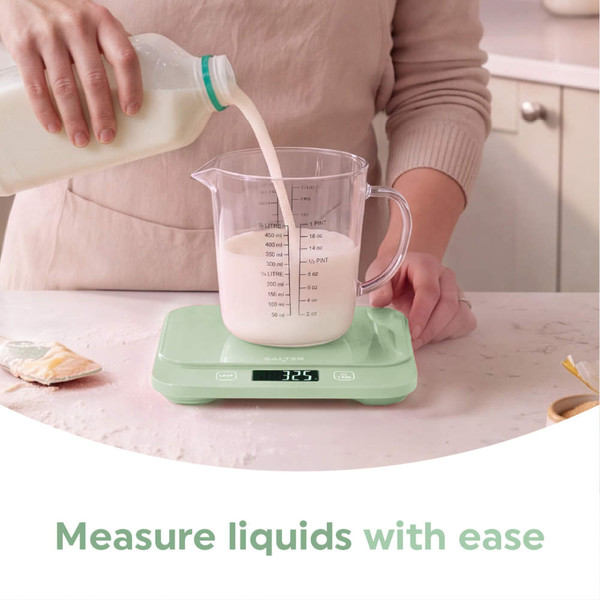 Digital kitchen scale in pastel green weighing crumble topping, pie and apples in background