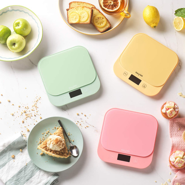 Set of pastel kitchen scales in green, yellow, and pink for baking on a worktop