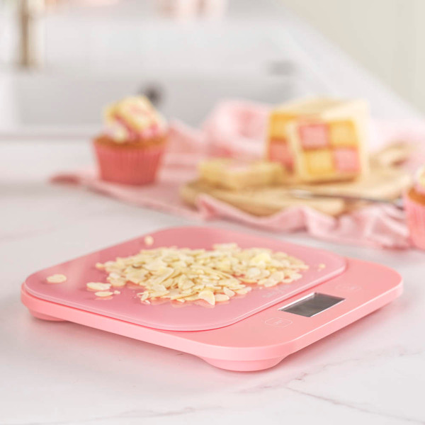 Pink digital kitchen scale with sliced almonds on top, shown on a countertop.