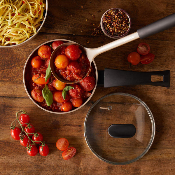 Non-stick saucepan filled with tomato and basil sauce, shown with spaghetti and fresh cherry tomatoes.
