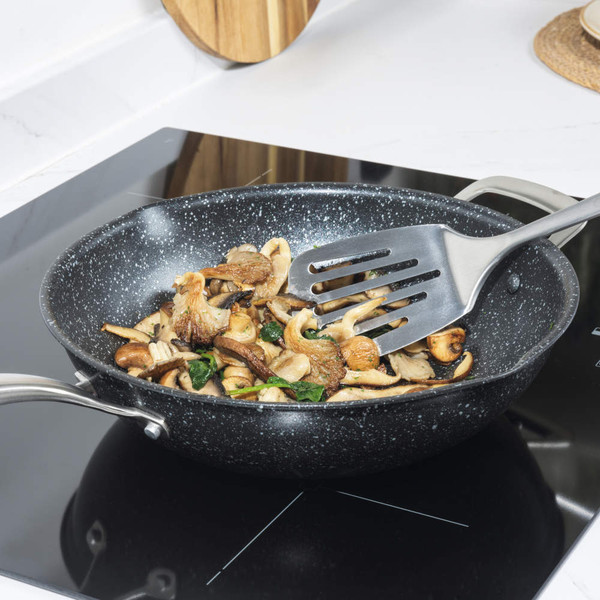 Silver non-stick frying pan with mushrooms on induction hob
