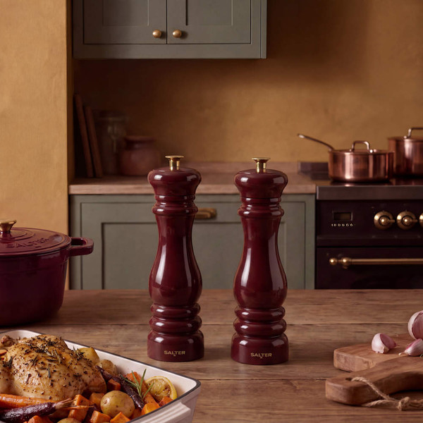 Set of two red Salter salt and pepper mills on wooden kitchen counter with herbs and bread