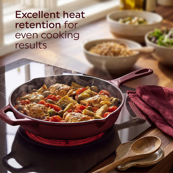 Red cast iron skillet with roasted cherry tomatoes and herbs on wooden table