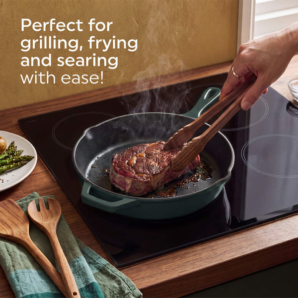 Green cast iron skillet with salmon fillet and asparagus on wooden board