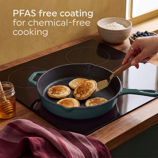 Green cast iron frying pan on hob with pancakes, hand flipping, kitchen scene