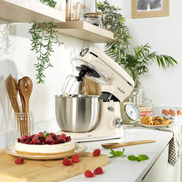 Cream stand mixer with stainless steel bowl and whisk attachment, angled side view.