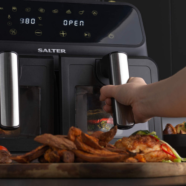 Salter dual air fryer in use, showing digital display and cooked food on a wooden board.