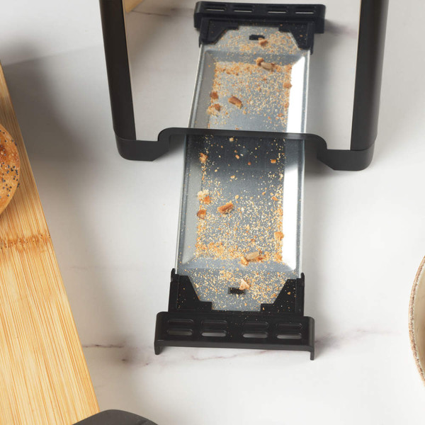 Toaster crumb tray partially removed, showing breadcrumbs for easy cleaning