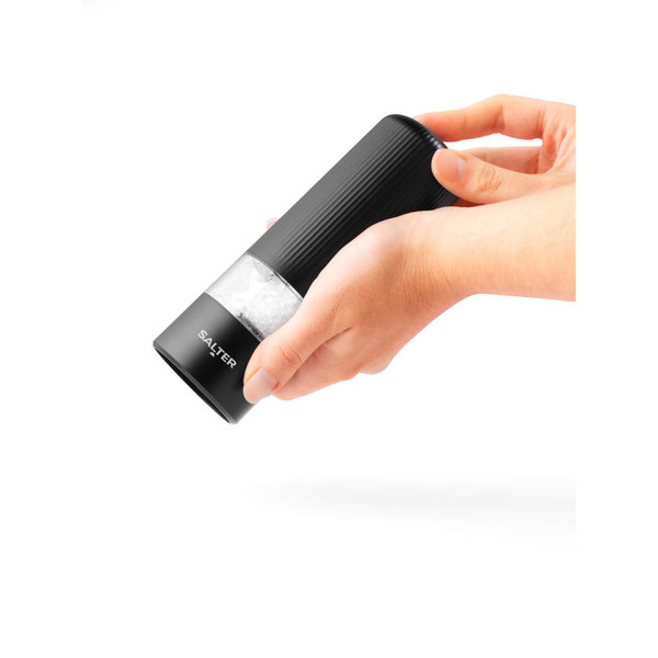 Hand holding black electric salt or pepper grinder showing grinding action