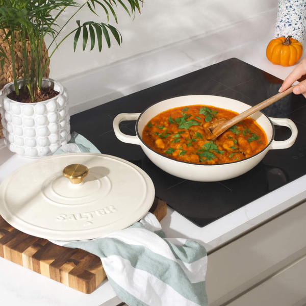 Cream cast iron casserole dish with lid, shown on hob with stew cooking