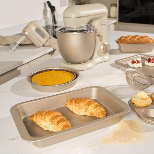 Cream stand mixer with bowl, rolling pin and gingerbread cookie dough on kitchen counter