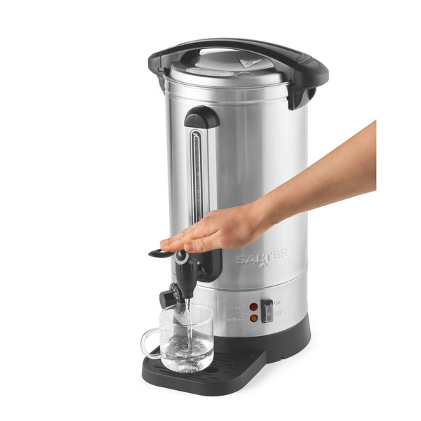 Hand dispensing hot water into a glass cup from a silver catering urn