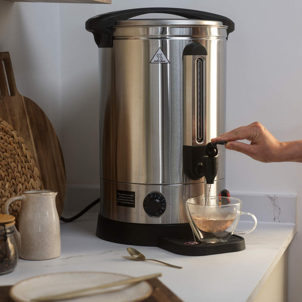 Stainless steel hot water urn with tap dispenser on kitchen counter