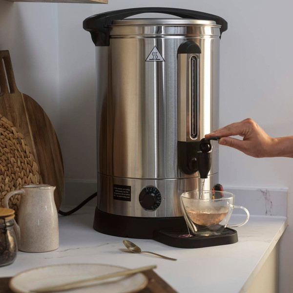 Stainless steel hot water urn with tap dispenser on kitchen counter