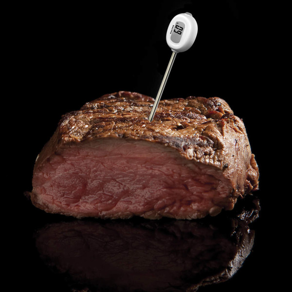 Digital meat thermometer inserted in medium-rare steak, showing temperature on display